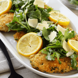 close up of breaded chicken topped with Lemon arugula salad