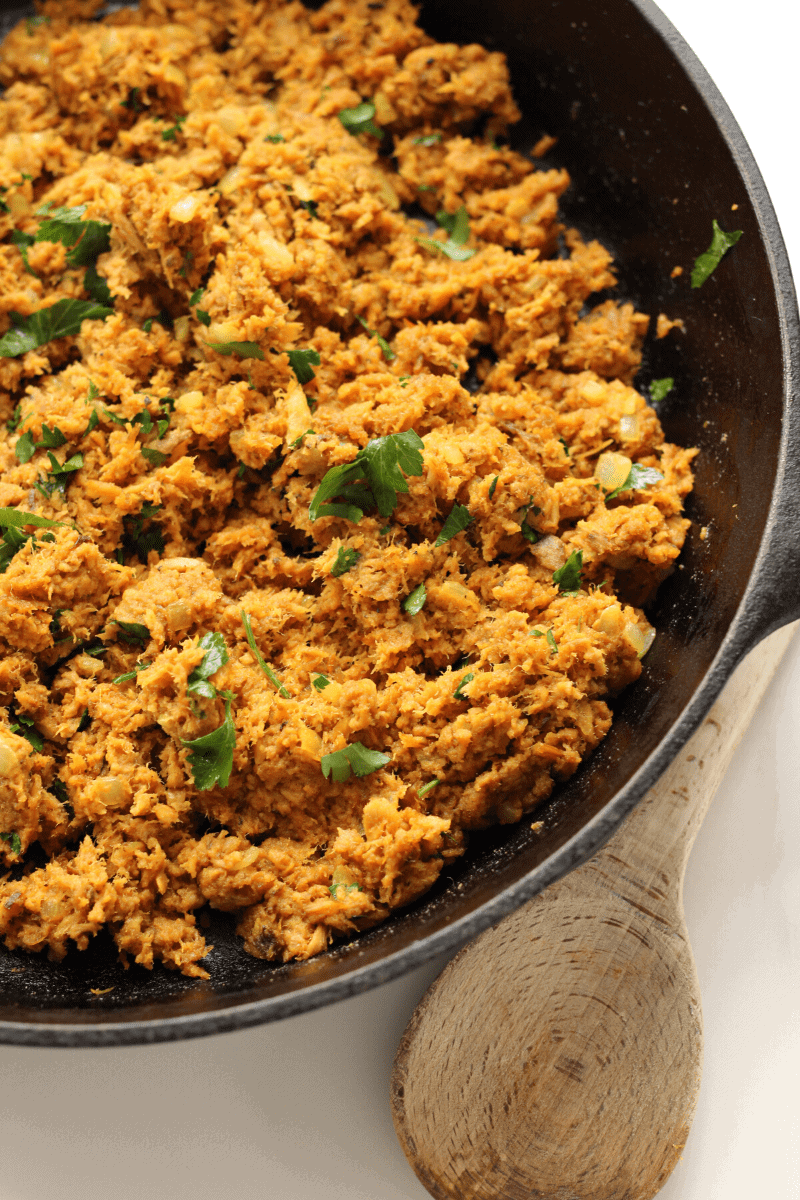 Overhead shot of Cape Verdean tuna that's been seasoned and browned in a large cast iron skillet and garnished with fresh parsley. Tuna has been prepared to make pastel.