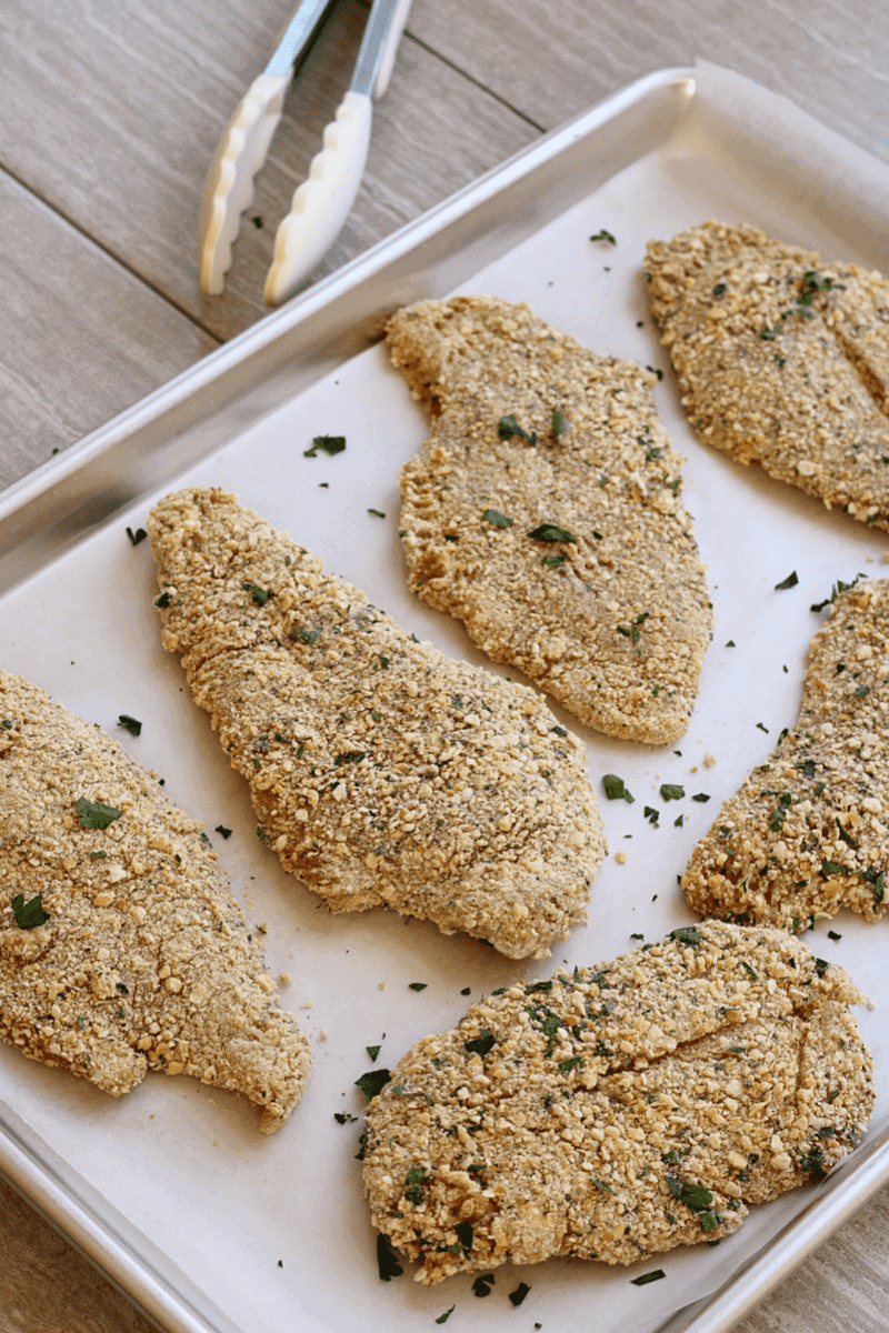 overhead shot of breaded chicken breast on a parchment lined baking sheet