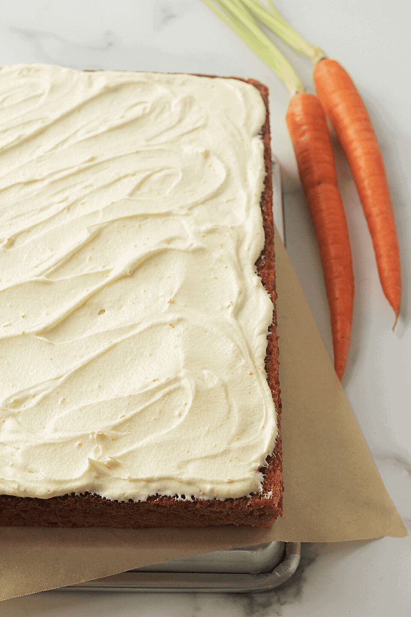 This is an angled shot that displays about 80% of my fluffiest carrot sheet cake that has been topped with whipped cream-cheese frosting.