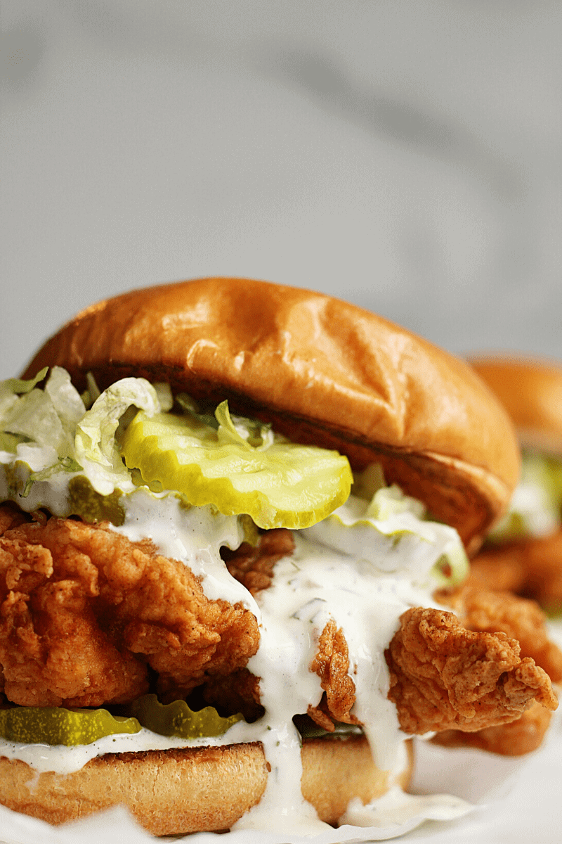 Spicy crispy buttermilk chicken sandwich closeup on a brioche bun with lettuce pickles and homemade ranch dressing.