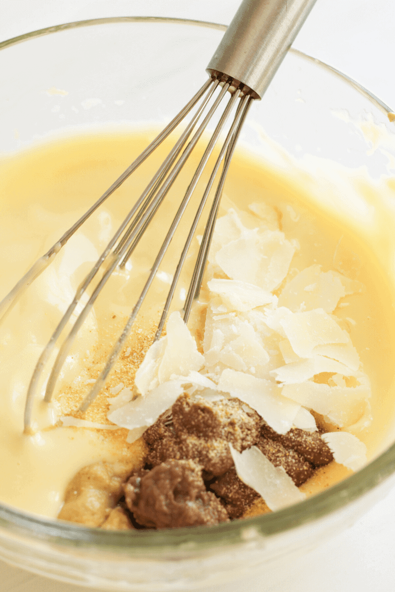 This image shows the parmesan, anchovy paste, dijon mustard and garlic powder to the Caesar dressing
