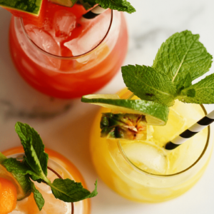 Overhead shot that displays cantaloupe, watermelon and pineapple aguas frescas and suggest to the reader how to serve and garnish the drink