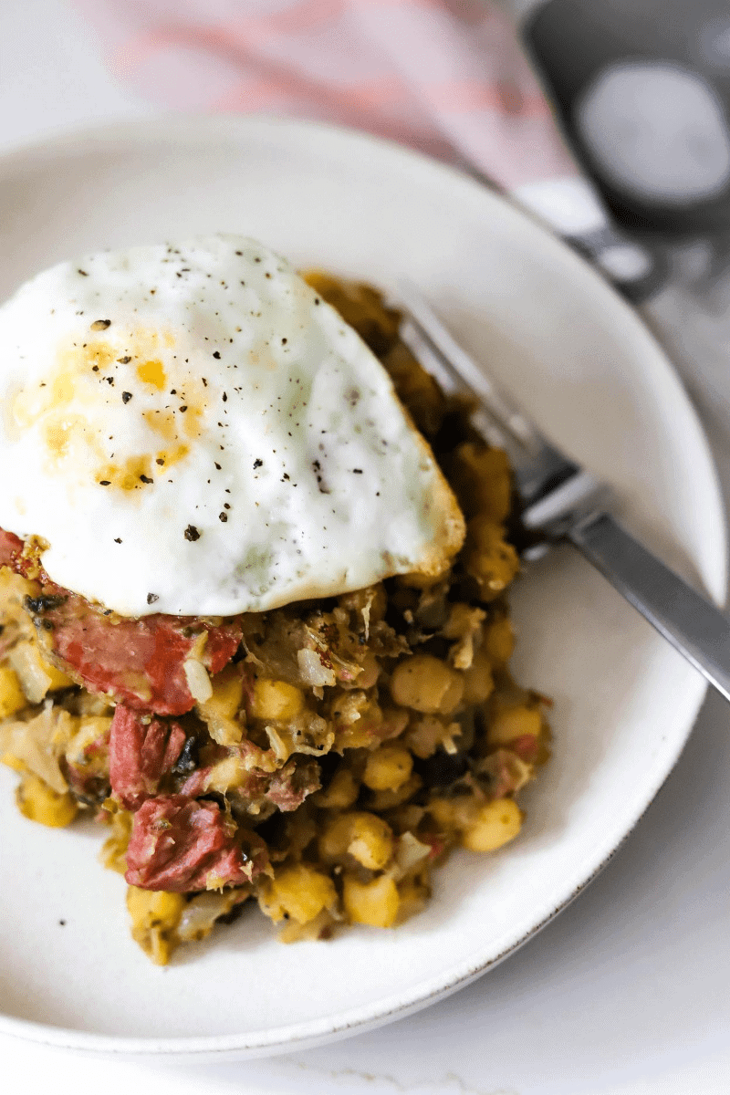 Cachupa refogado (also known as cachupa guisado) - the image shows cachupa that is fried the next day and topped with a fried egg.