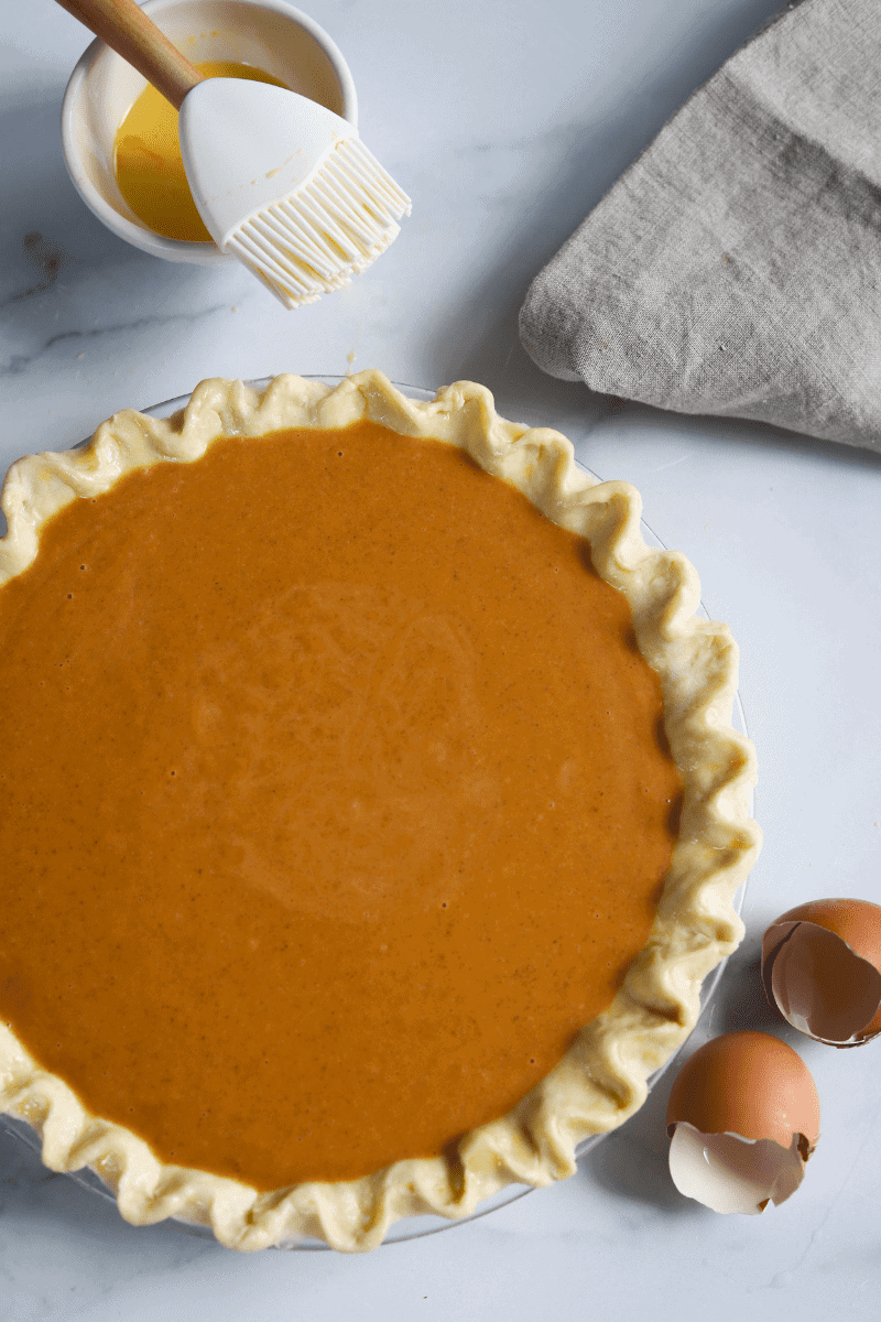 close up photo of a homemade pie shell filled with pumpkin filling