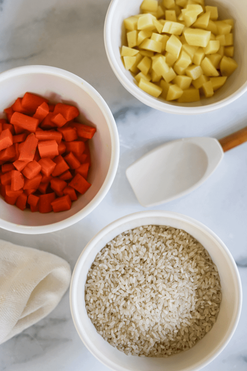 Overhead photo of some basic ingredients used to make Cape Verdean Canja- diced carrots, diced potatoes and medium grain rice