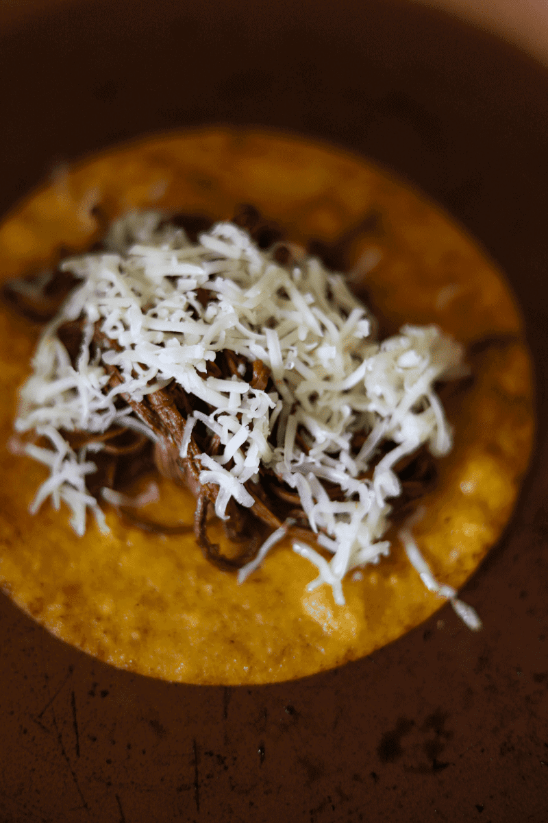 Close up shot of a birria taco topped with melted monterey jack cheese being fried in anon-stick skillet