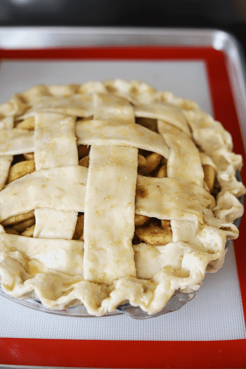 This is a photo of an unbaked apple pie with a lattice pie crust right before it goes into the oven. The pie is baked on a silicone baking mat on a metal baking sheet.