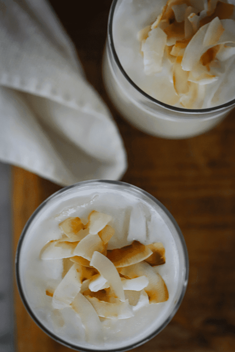 two glasses of Cape Verdean coconut pontche garnished with toasted coconut flakes