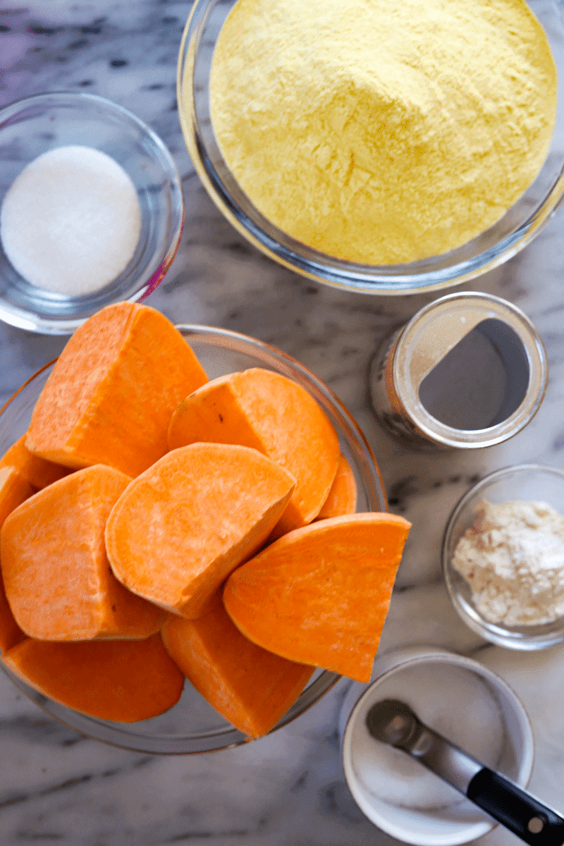 This is a photo that displays all of the ingredients to make sweet potato gufong. Clockwise order : granulated sugar, cornmeal, baking powder, all-purpose flour, salt and sweet potatoes.