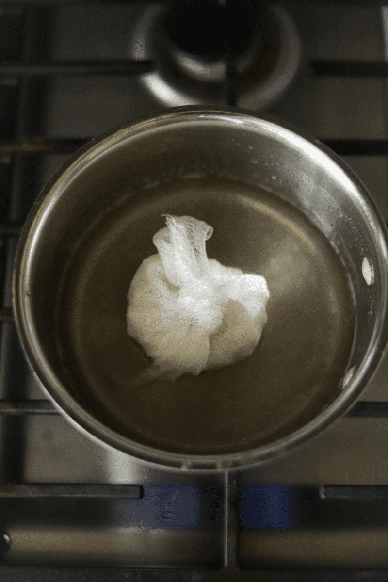 This is a photo of the coconut flakes wrapped in cheesecloth and placed in a small pan of sugar and water to make Cape Verdean coconut pontche