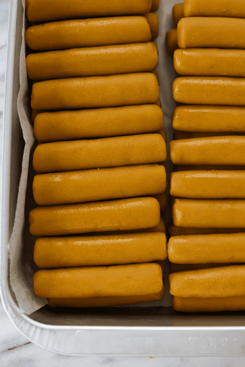 This is a photo of 40-50 uncooked gufong lined up in a metal baking pan before being fried