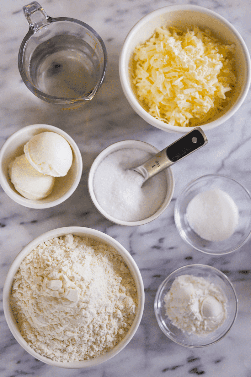 This is an overhead photo of ingredients needed to make an easy shortening pie crust: grated butter, shortening, salt, sugar, all-purpose flour, and cornstarch
