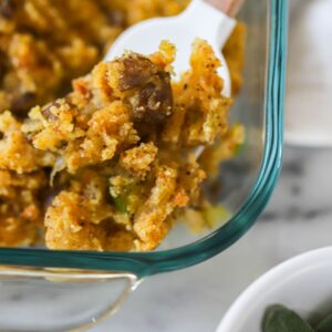 baked cornbread stuffing in a glass baking dish scooped with a spoon.