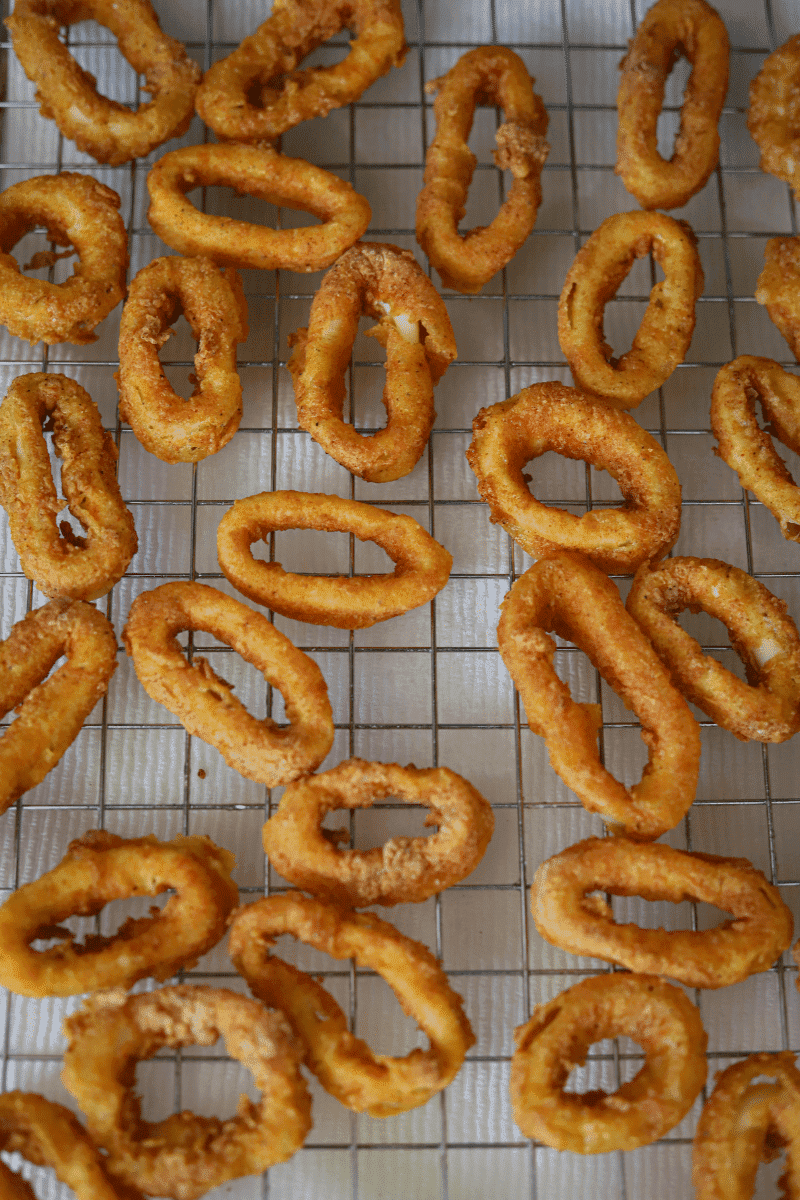 Fried calamari rings (lulas fritas) on a metal cooling rack