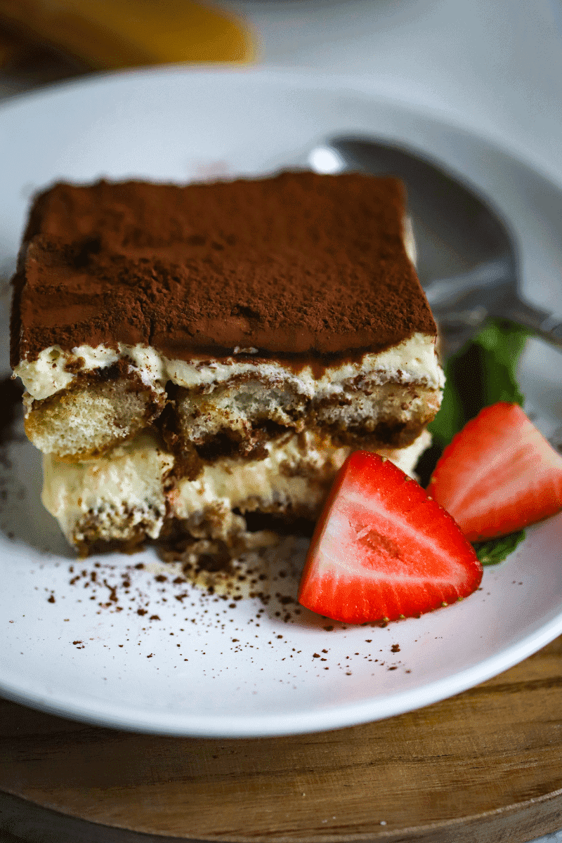 easy classic tiramisu recipe- slice on white plate with strawberry garnish