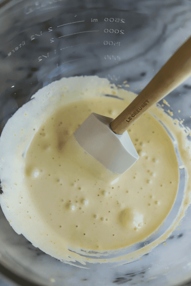 easy tiramisu recipe-overhead photo of beaten egg yolks and sugar, it's custard-like and pale in color. A wooden spatula is shown but the yolks should be beaten on high speed with a stand mixer or electric beater.