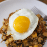 Close up photo of cachupa guisado (refogado) topped with a fried egg (sunny-side up)