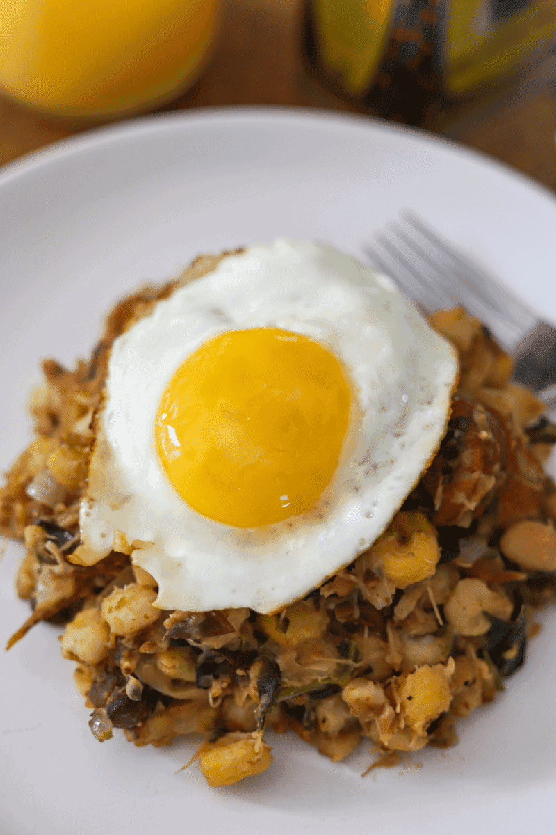 Close up photo of cachupa guisado (refogado) topped with a fried egg (sunny-side up)