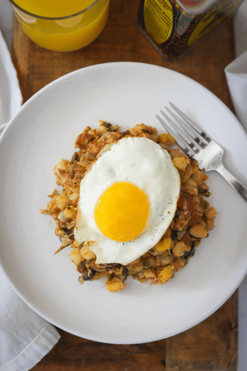 Overhead photo of cachupa guisado (refogado) topped with a fried egg (sunny-side up)