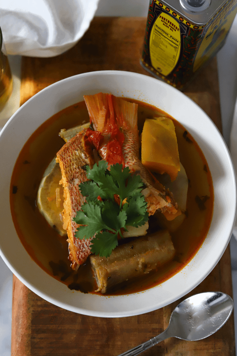 bowl of caldo de peixe shown with red snapper, squash, potatoes and banana and fresh cilantro.