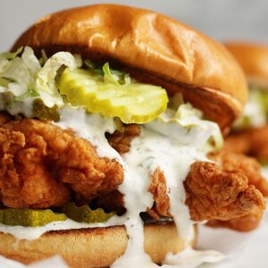 crispy buttermilk chicken sandwich on a brioche bun with pickles and ranch drizzle