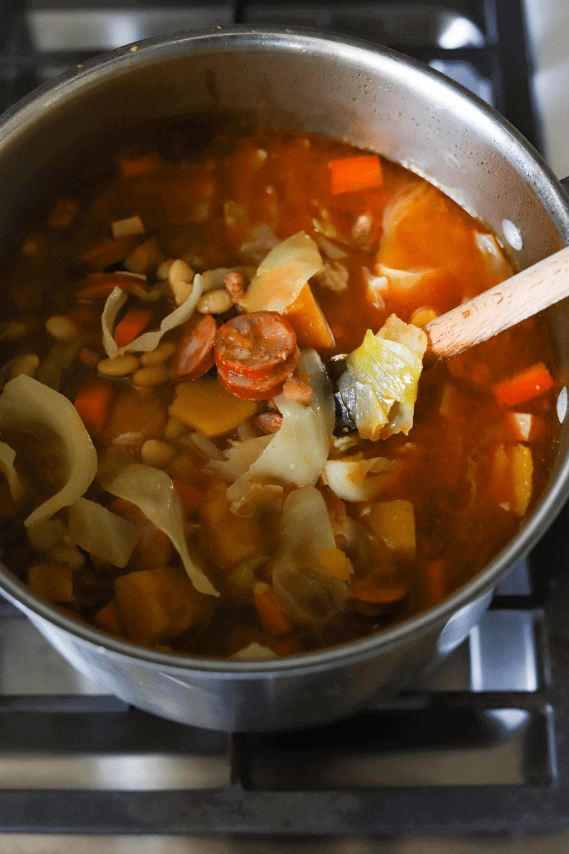 process shot of feijoada in later cooking stage with meat and vegetables