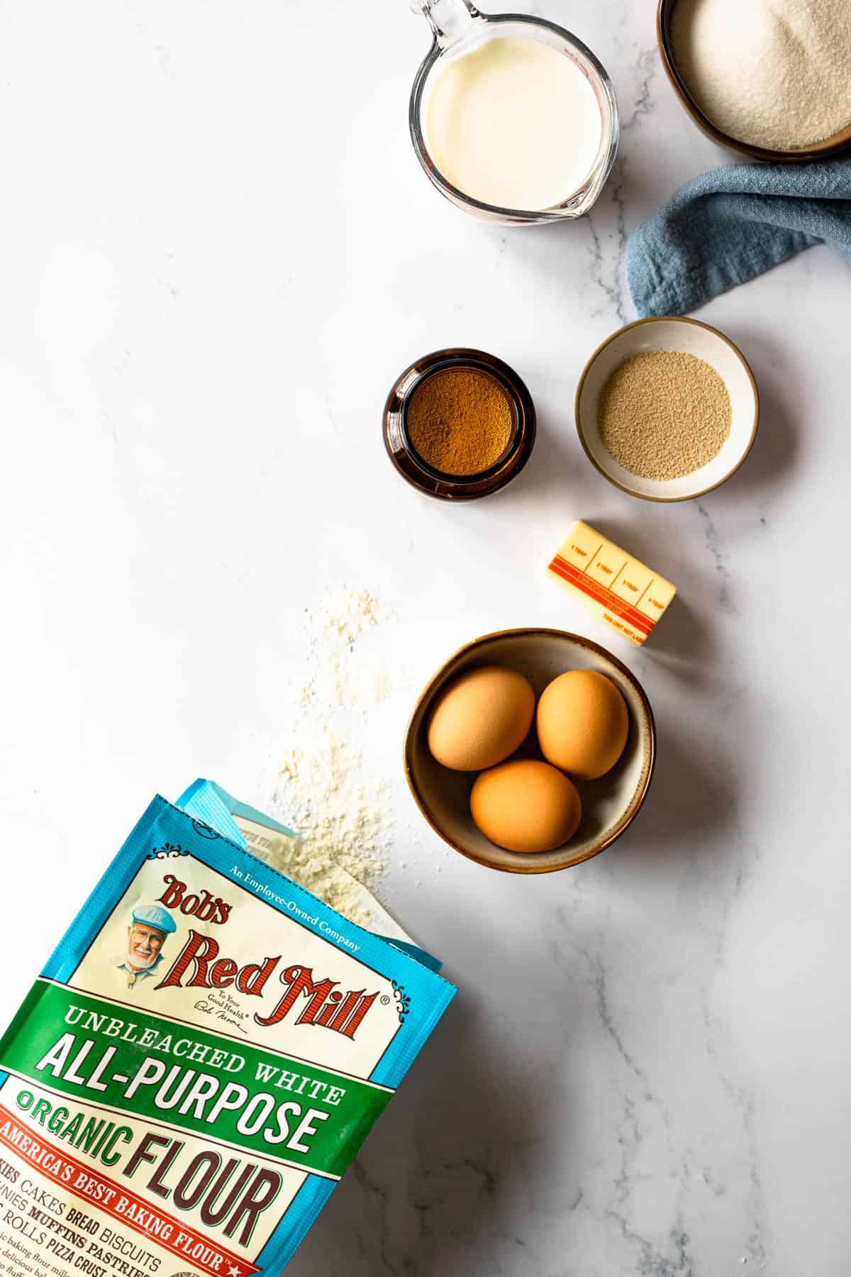 ingredients for portuguese sweet bread- sugar, milk, yeast, butter, eggs, flour (salt not shown).