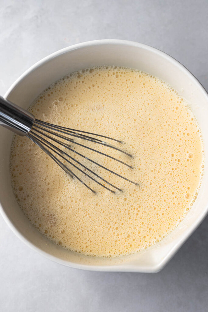 bowl of morir soñando-combined orange juice and condensed milk shown with whisk