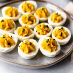 deviled eggs with miracle whip filling on a platter garnished with parsley