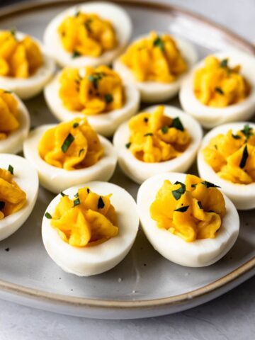 deviled eggs with miracle whip filling on a platter garnished with parsley