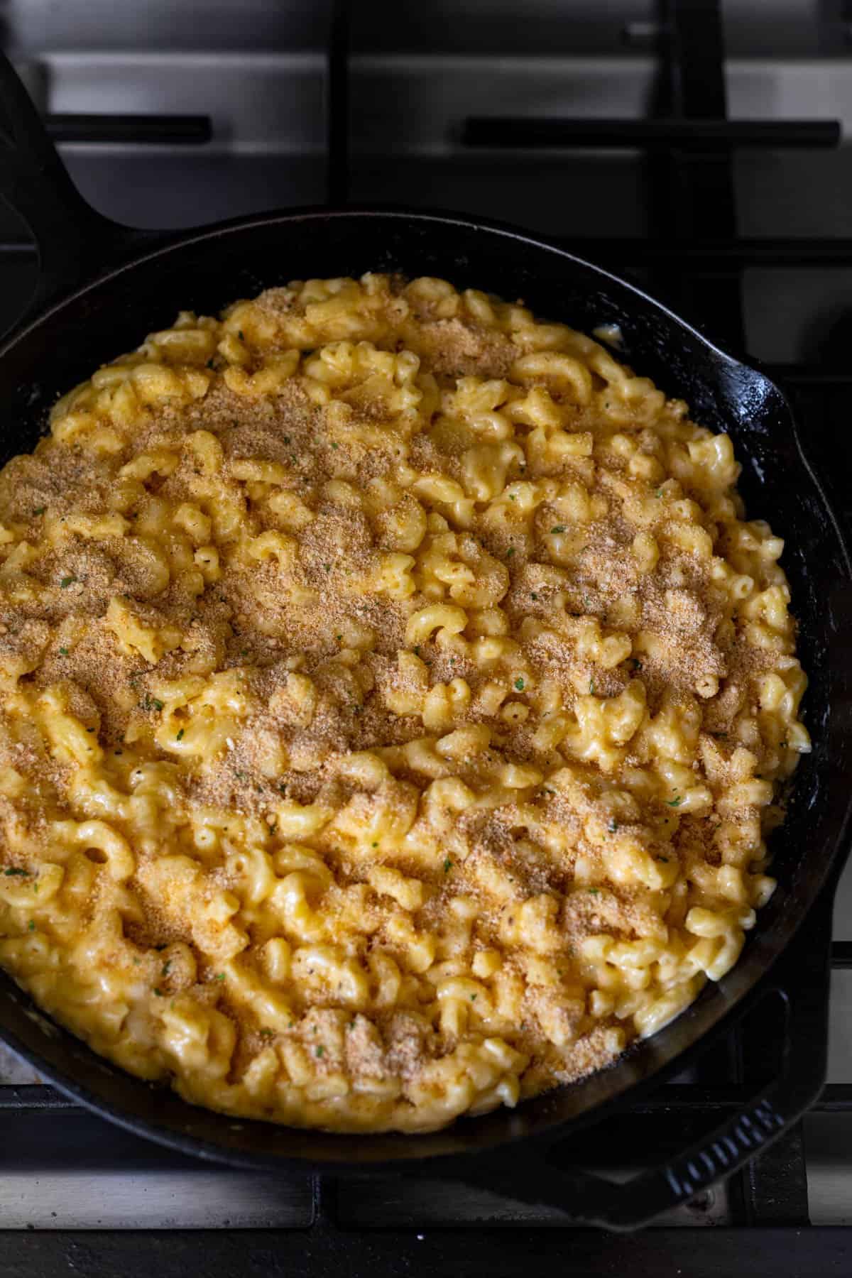 unbaked mac and cheese in cast iron skillet topped with breadcrumbs