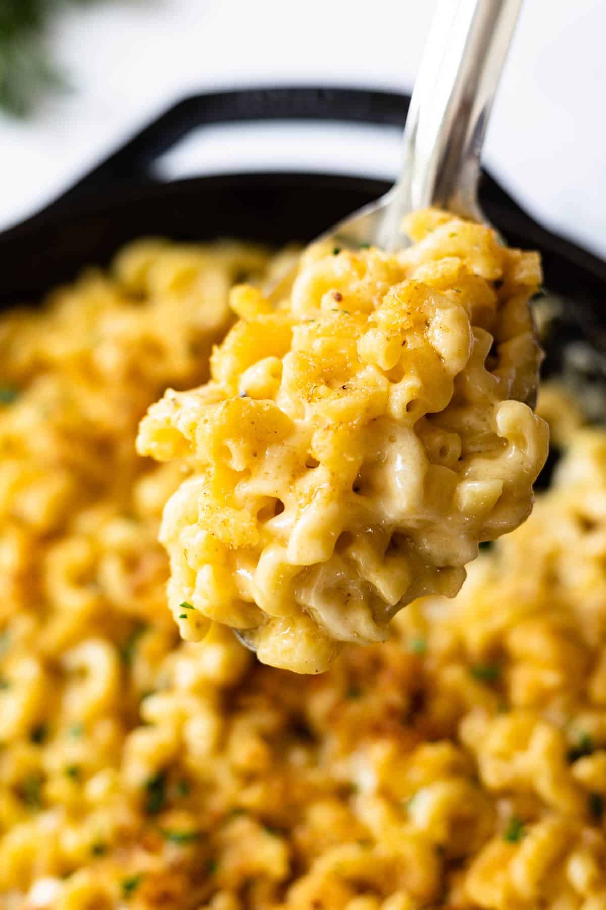 large spoonful of creamy cheese mac and cheese prepared in a cast iron skillet