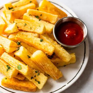 plate of cassava fries served with ketchup and garnished with cilantro and sea salt