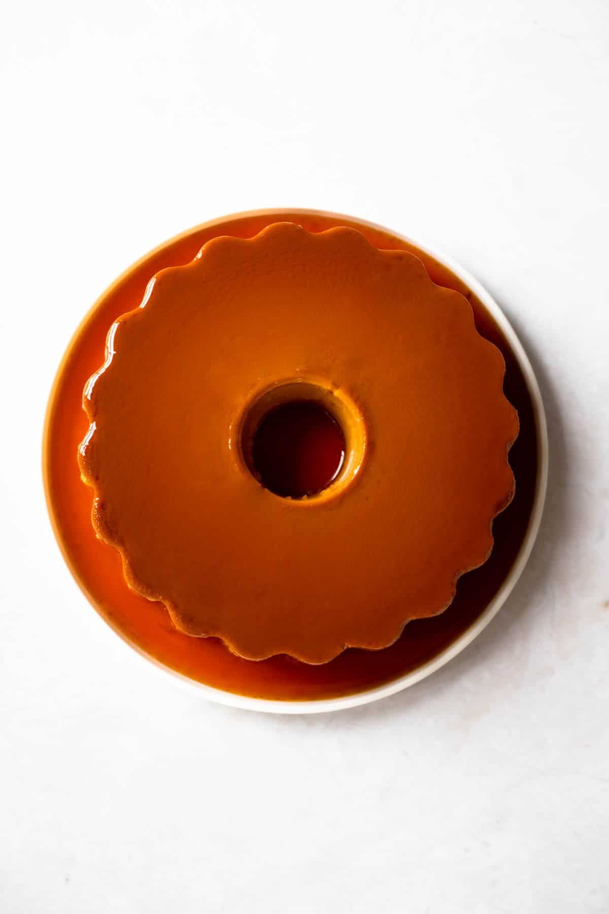 un-molded flan on a plate with rich, amber-colored caramel syrup