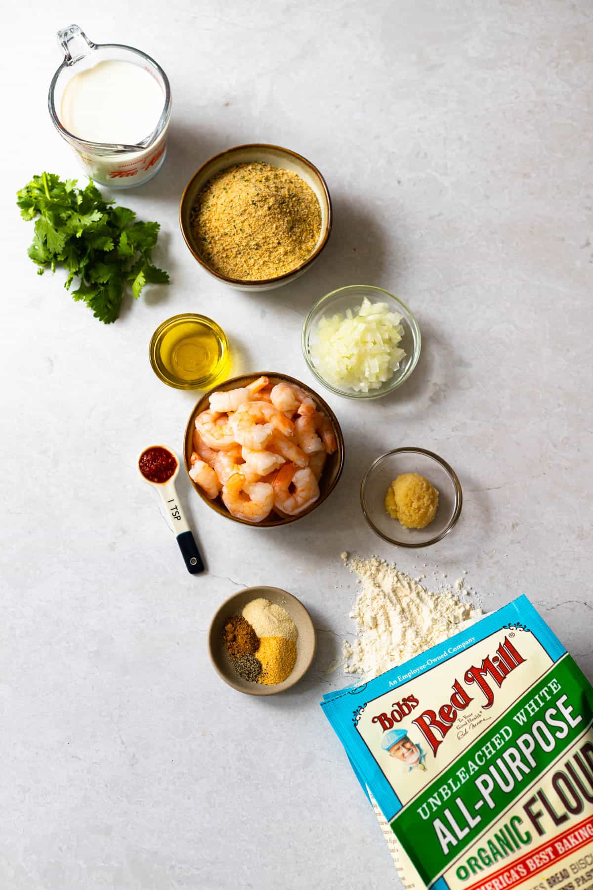 ingredients for shrimp rissois - heavy cream, breadcrumbs, onion, crushed garlic, flour, seasonings, cooked shrimp, crushed red peppers, olive oil, cilantro, butter not shown