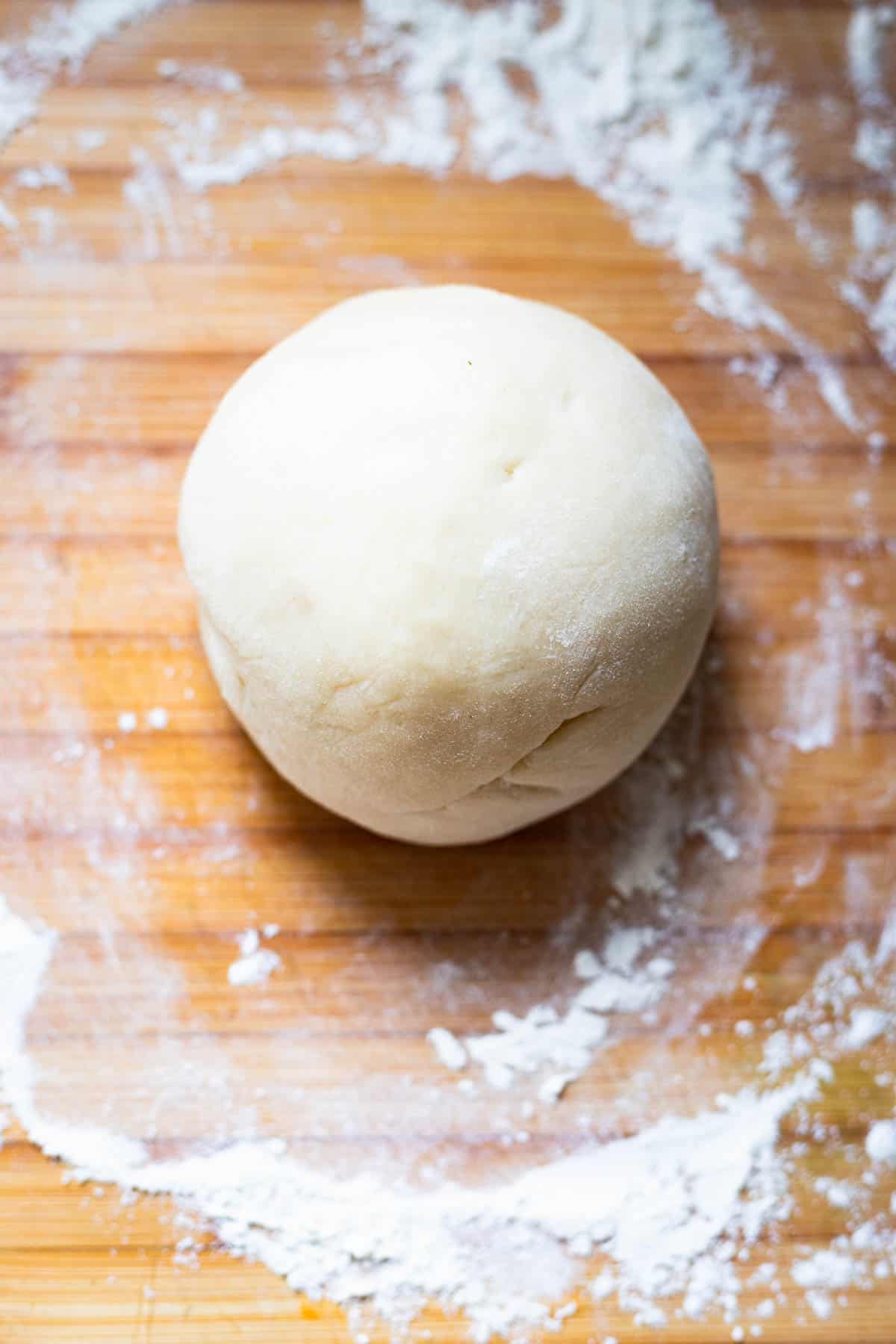 ball of dough for rissois on a wood cutting board