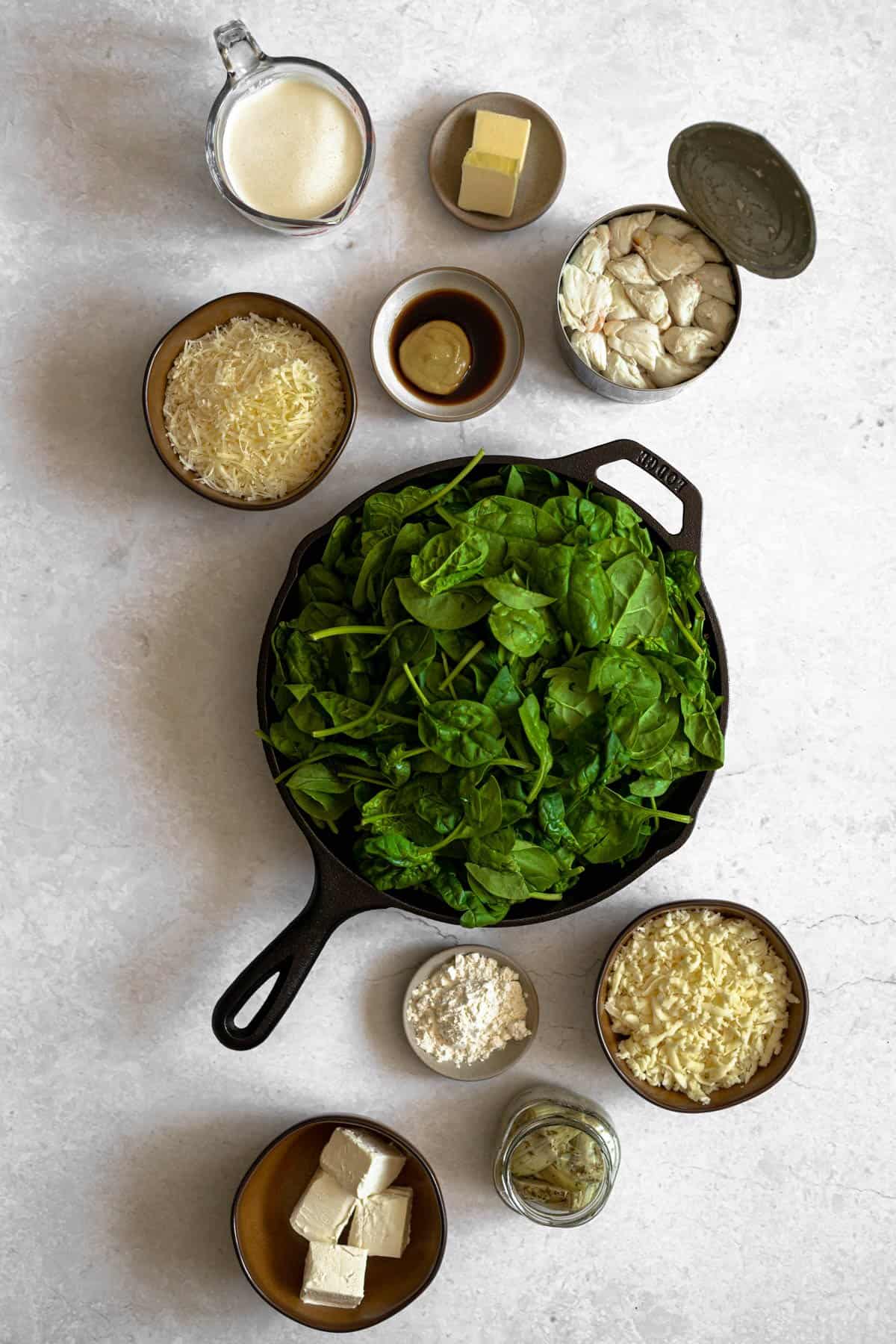 ingredients for spinach artichoke and crab dip: heavy cream, butter, worcestershire, dijon, shredded parmesan and mozzarella cheese, fresh spinach, flour, jarred artichokes and cream cheese 