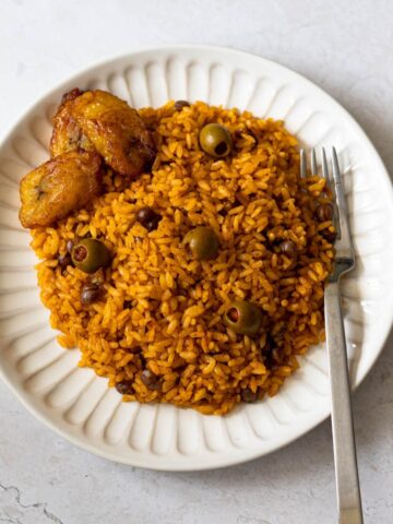 pigeon peas with rice and olives on a white plate with a fork.