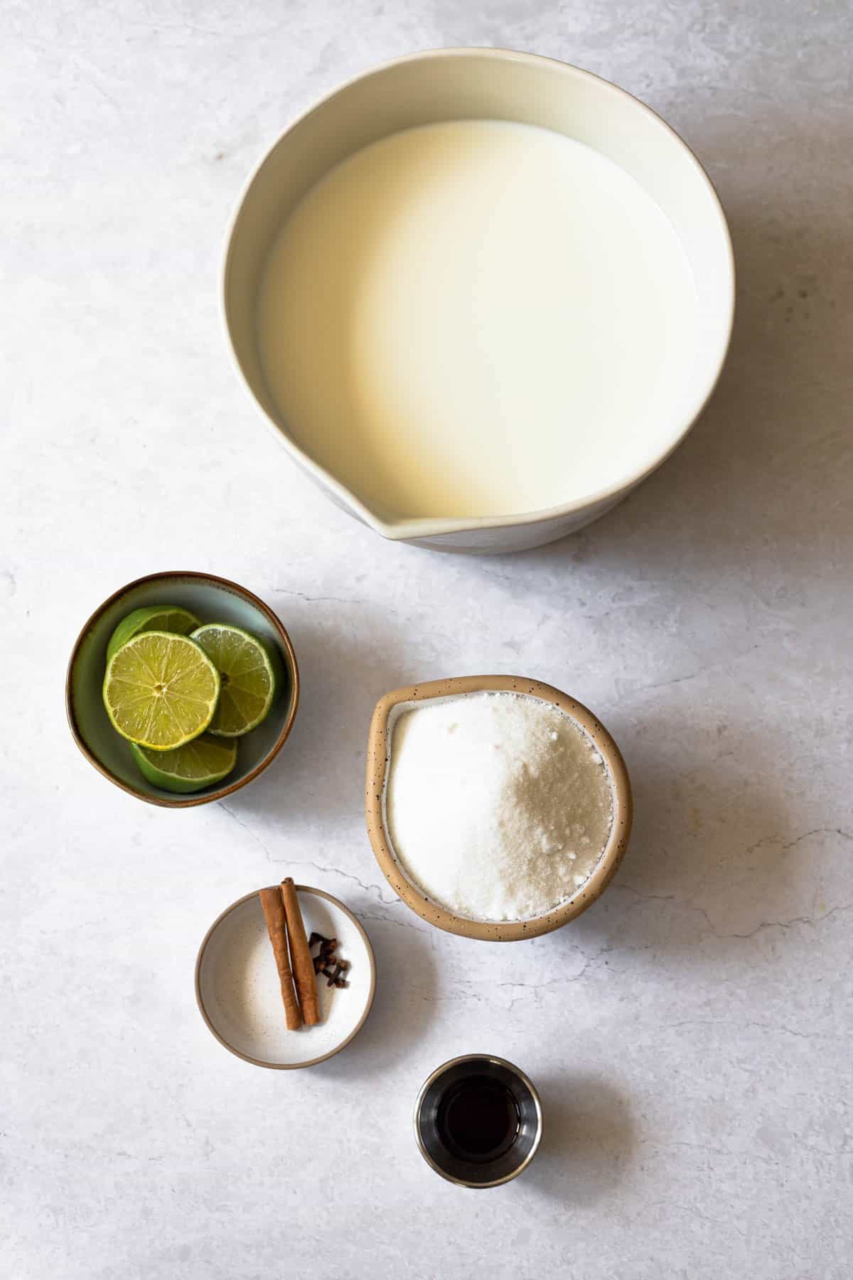 ingredients needed - fresh milk, fresh limes, granulated sugar, cloves, cinnamon sticks and vanilla extract