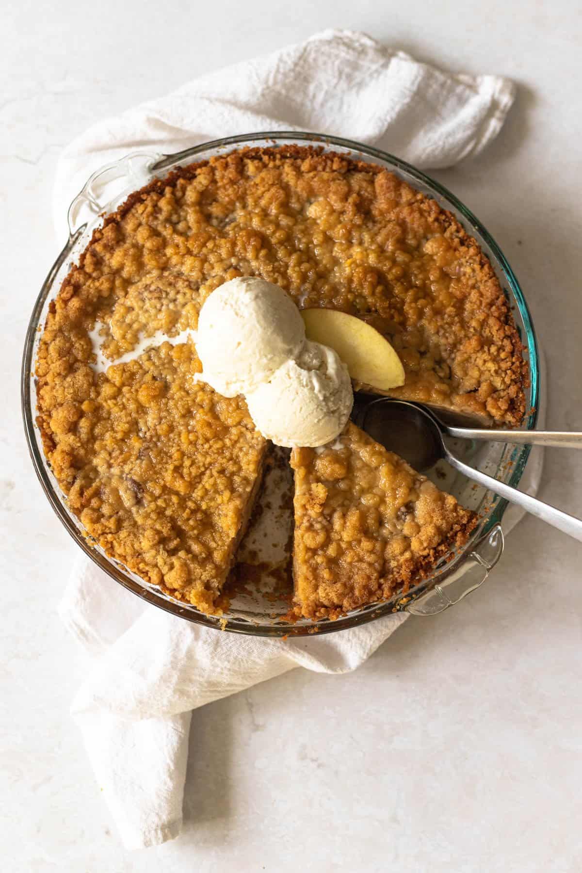 apple pie with graham cracker crust topped with a scoop of vanilla ice cream.