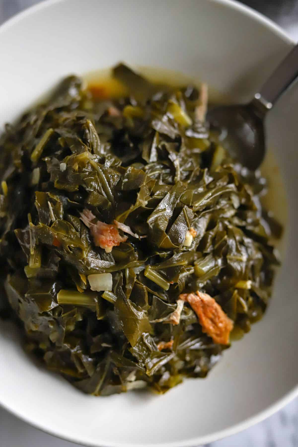 collard greens with smoked turkey in a white bowl with a fork.