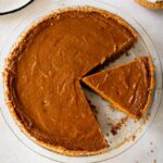 sliced sweet potato pie with graham cracker crust in a glass pie plate.