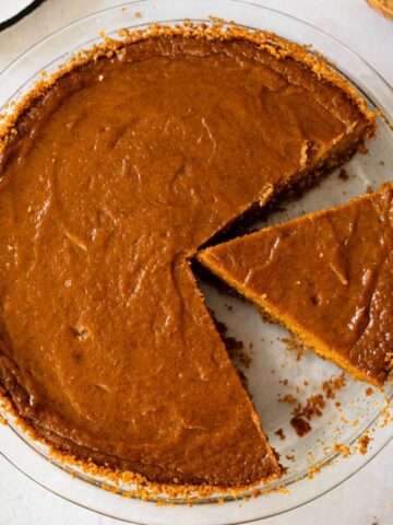 sliced sweet potato pie with graham cracker crust in a glass pie plate.