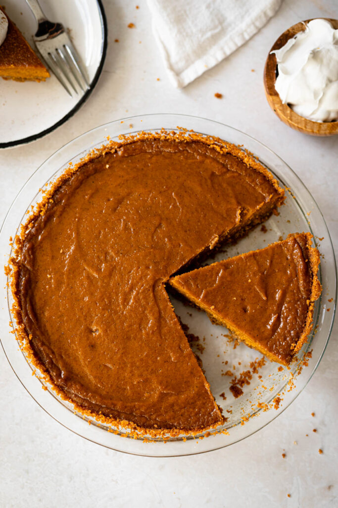 sliced sweet potato pie with graham cracker crust in a glass pie plate.