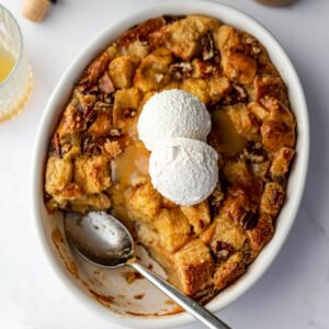 bread pudding in a round baking dish topped with bourbon sauce and whipped topping.