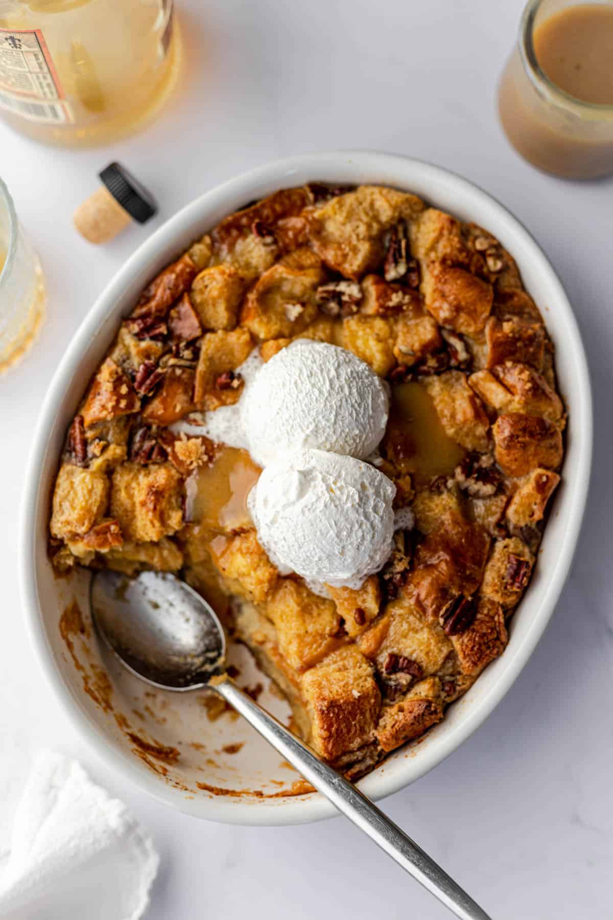 bread pudding in a round baking dish topped with bourbon sauce and whipped topping.