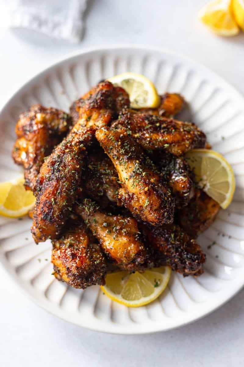 lemon pepper wings garnished with lemon slices and parsley on a white plate.