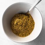 homemade lemon pepper seasoning in a bowl with a spoon.