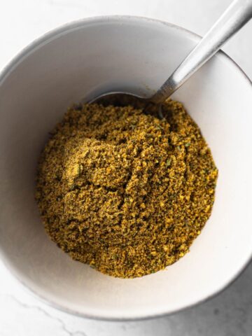 homemade lemon pepper seasoning in a bowl with a spoon.